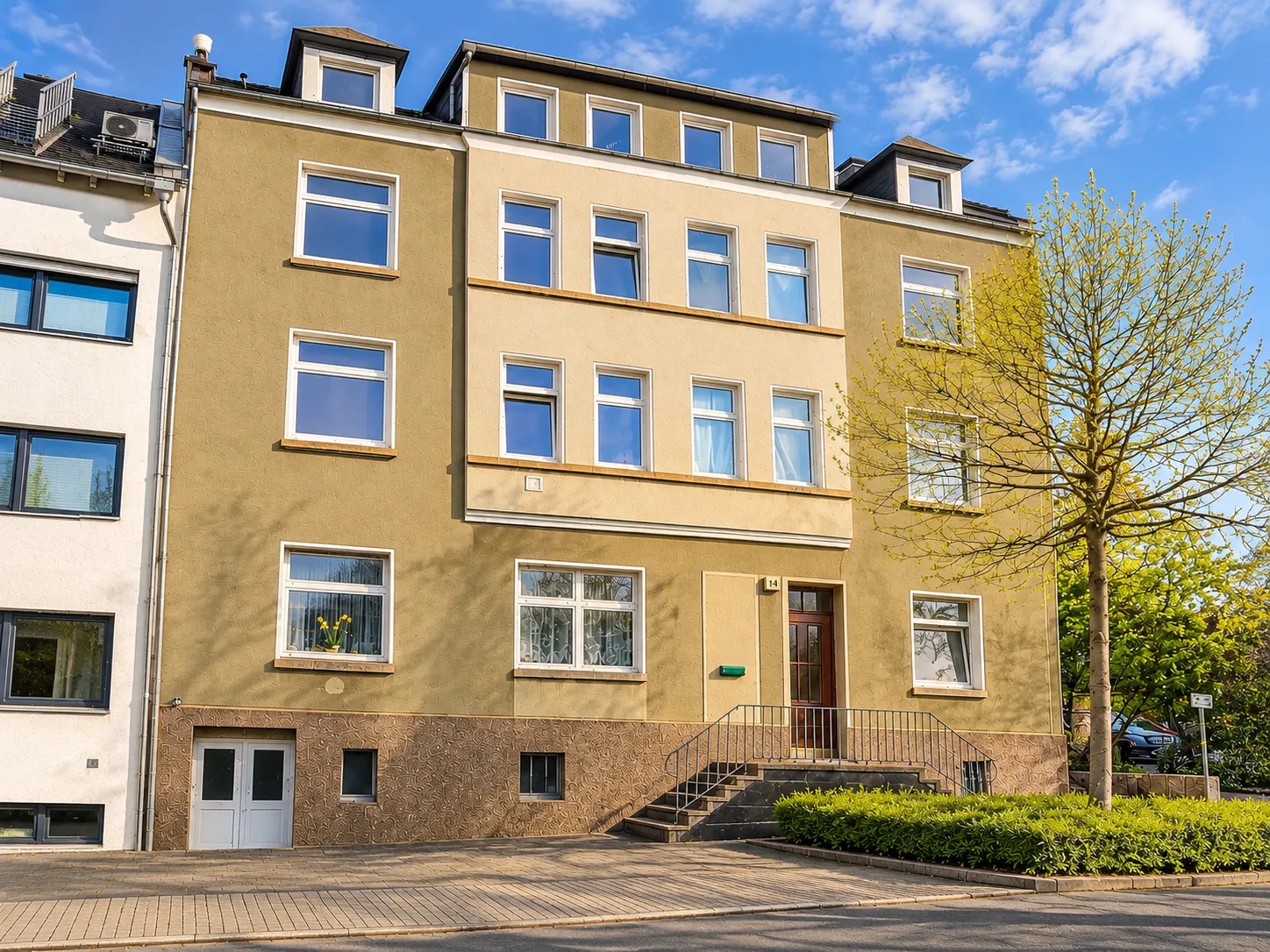 Ockerfarbenes Mehrfamilienhaus mit Freitreppe zum Eingang