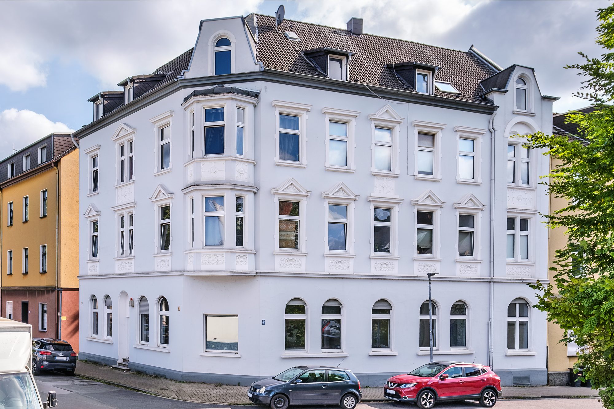Weiß gestrichenes Gründerzeit-Eckhaus mit Erker und Stuckfassade